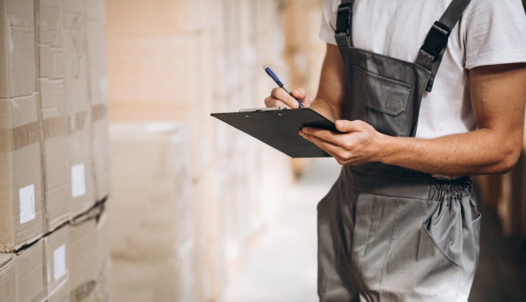 Warehouse worker checking stacked boxes on shelves